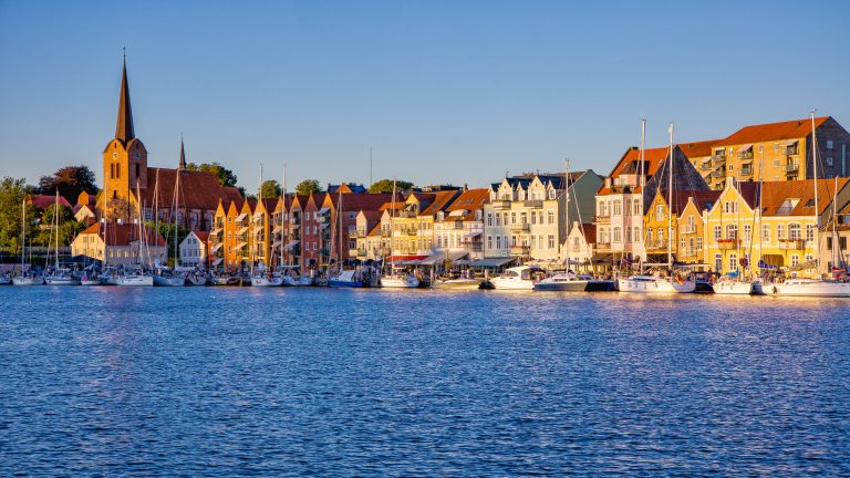skyline with blue sky and evening sunlight in the danish city of Sonderborg, overlooking the promenade with sailboats.