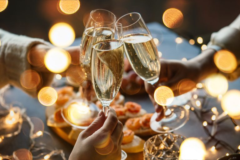 Friends celebrating Christmas or New Year eve party with champagne or sparkling wine.